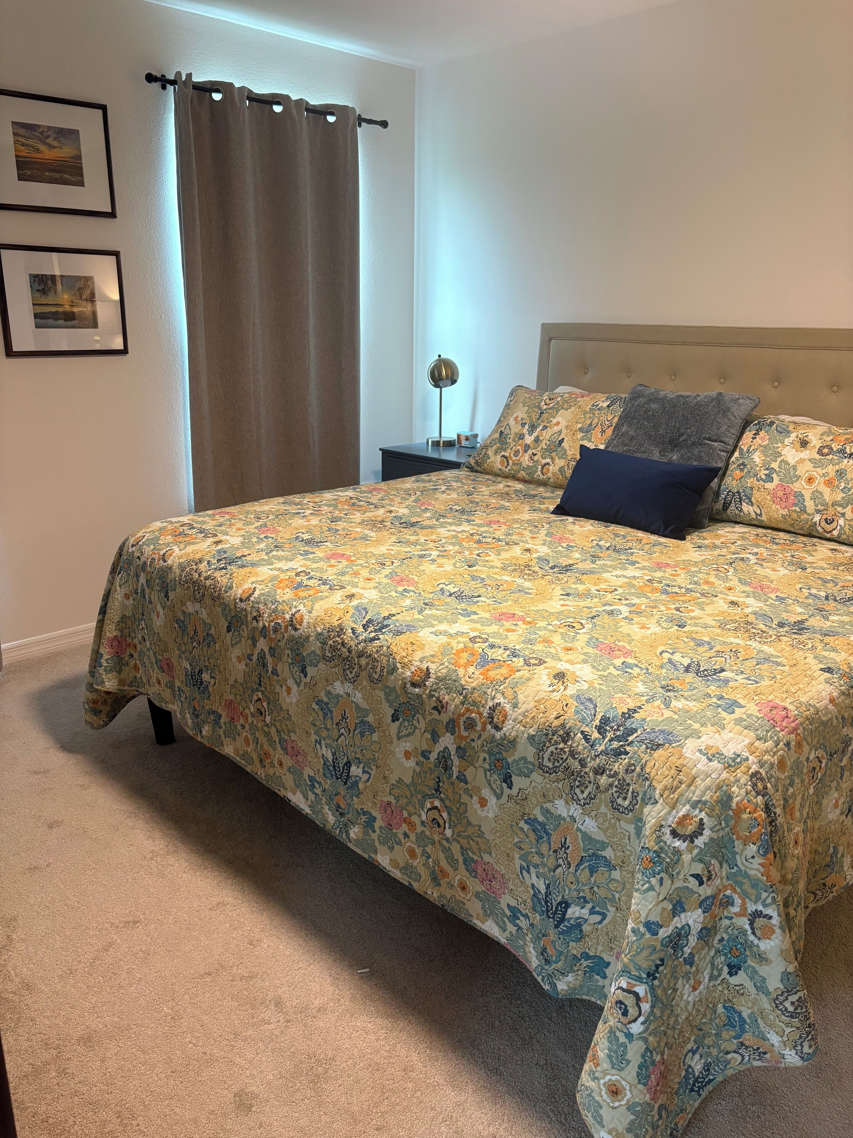 Una camera da letto con un letto grande, un comodino, una lampada e due quadri appesi al muro.