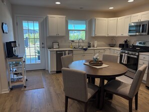 A modern kitchen with white cabinets, a dining table with chairs, a coffee machine, and a dishwasher. - 3-bedroom house in The Village of Shadybrook, only minutes from Eastport. (Wildwood)
