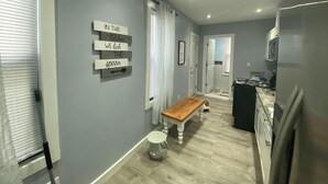 A modern kitchen with a wooden bench, a sign on the wall, and a refrigerator. - Work, Crew & Family Stay Near Downtown Reading (Reading)