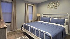 A bedroom with a bed, curtains, a lamp, and a wall decoration. - Work, Crew & Family Stay Near Downtown Reading (Reading)