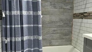 A bathroom with a shower curtain, a bathtub, and a small rug. - Work, Crew & Family Stay Near Downtown Reading (Reading)
