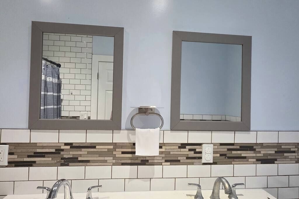Ein Badezimmer mit zwei Spiegeln, einem Handtuchhalter und einer gefliesten Rückwand.