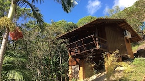 A wooden cabin with a balcony, surrounded by tropical vegetation. - Pousada Porto Belo (Porto Belo)
