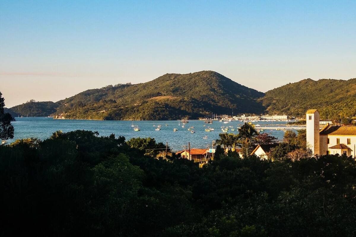 Une ville côtière dotée d’un port de plaisance, de bâtiments et de collines en arrière-plan.