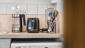 Eine Küche mit Kaffeemaschine, Toaster und Besteckhalter auf der Arbeitsfläche.