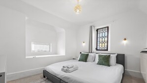 Ein modernes Schlafzimmer mit einem großen Bett, einem Fenster, einem integrierten Schreibtisch und einer außergewöhnlichen Leuchte.