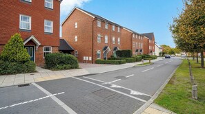 A residential street with brick houses, a clear sky, and a pedestrian crossing.