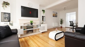 A modern living room with a flat-screen TV, a fireplace, and a comfortable seating area.