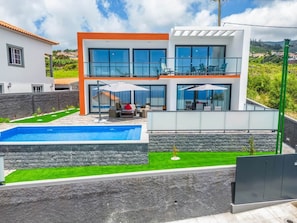 A modern two-story house with a swimming pool, a balcony, and a well-maintained lawn. - Sea View Apartment in Calheta, Madeira | Casa Teixeira (Estreito da Calheta)