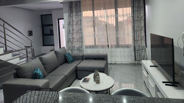 A modern living room with a sectional sofa, a small round table, and a flat-screen TV. - Luxury house with swimming pool Tarrafal, close to the beach (Tarrafal)