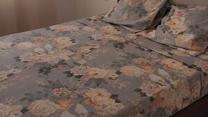 A single bed with a floral bedspread and matching pillows in a room with a plain wall and a visible light switch. - Luxury house with swimming pool Tarrafal, close to the beach (Tarrafal)