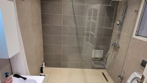 Et moderne badeværelse med bruser, toilet og vask.