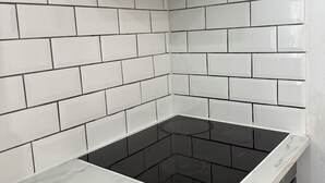 A kitchen with white subway tiles, a black induction cooktop, and a black range hood. - Stylish 3-Bed with Smart TVs, Parking & Workspace (Kettering)