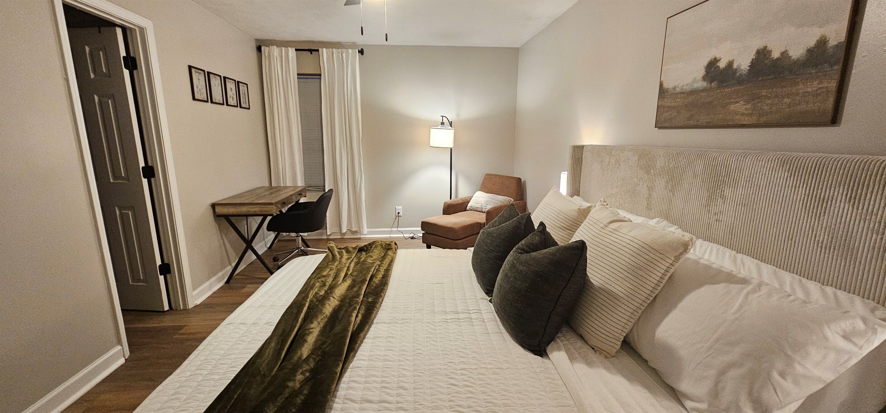 Ett hotellrum med en säng, ett skrivbord, en stol och en lampa.