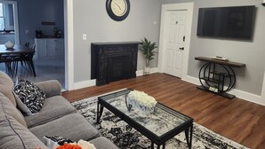 Un salon comprenant un canapé, une table basse, une cheminée et un téléviseur fixé au mur.