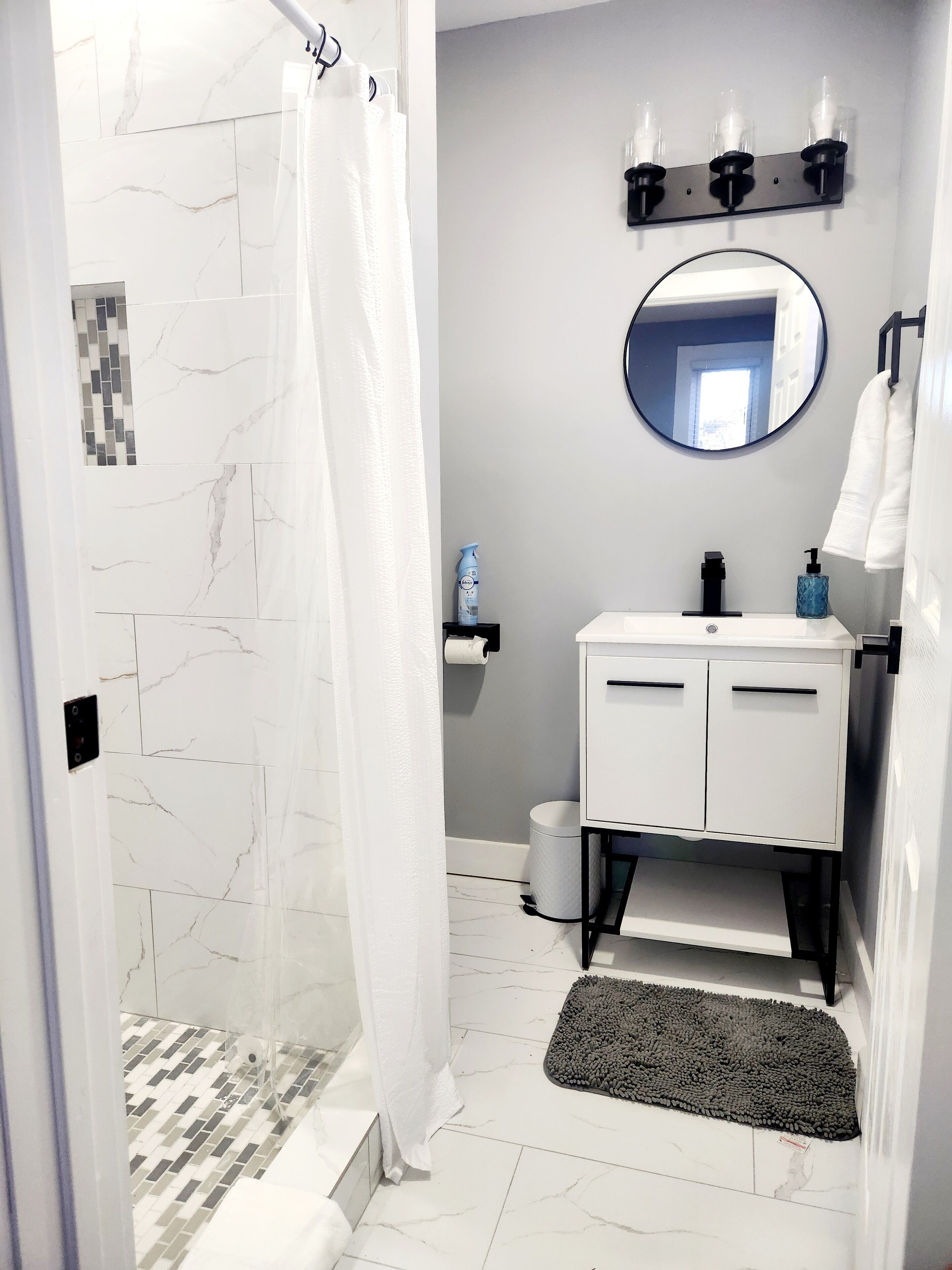 Une salle de bain avec une douche, un lavabo avec un miroir et un porte-serviettes.