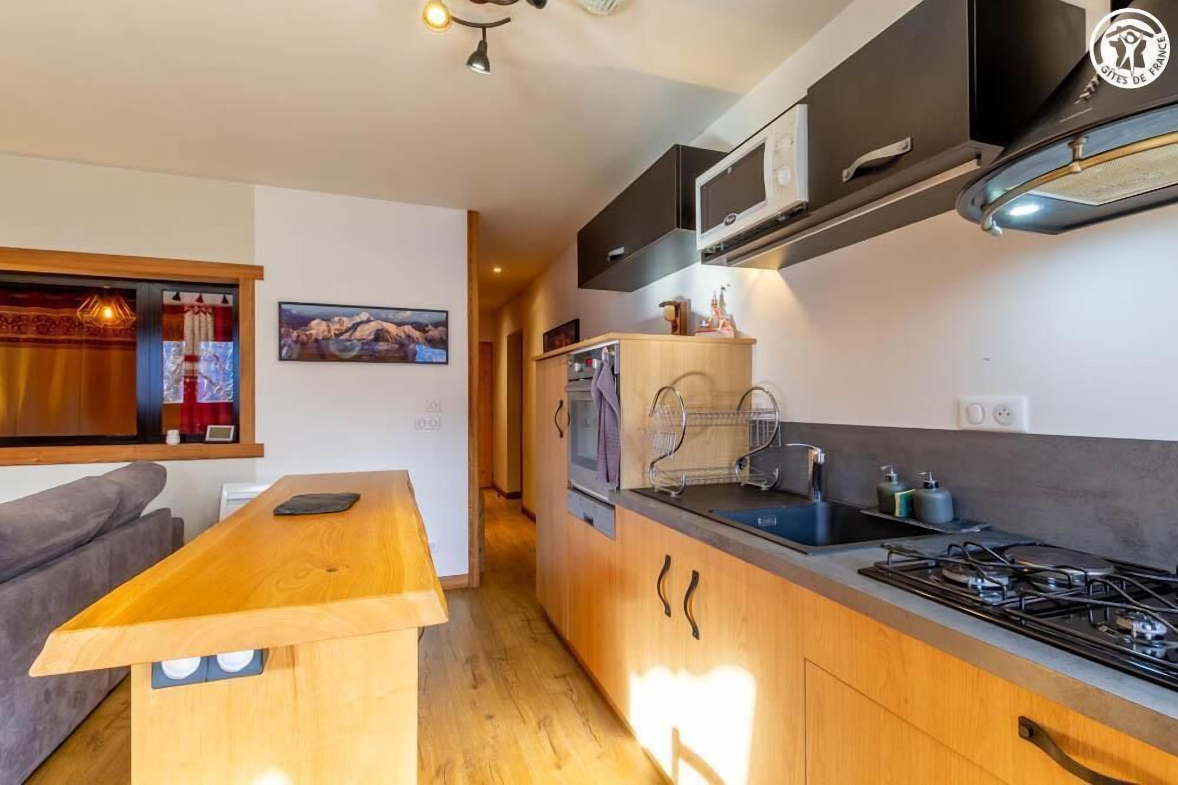 A modern kitchen with wooden cabinets, a built-in stove, and a small island with a sink.
