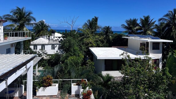 A coastal residential area with white buildings, a view of the ocean, and palm trees. - Breakview Penthouse 3BR  Retreat @ Encuentro Beach (Cabarete)