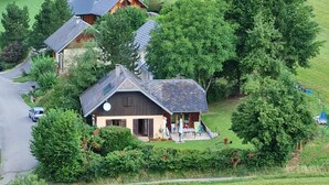 A rural house with a sloped roof, surrounded by lush greenery and a paved driveway. - GITE DES FONTANETTES (LA COMPOTE)