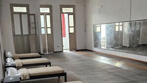 Een kamer met vier bedden tegen de muur geplaatst, een grote spiegel en een deur naar een andere kamer.