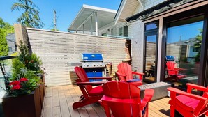 A wooden deck with red Adirondack chairs, a barbecue grill, and a large window. - Modern family home w/2 master suites. Close to stadium downtown, & shops. (Vancouver)
