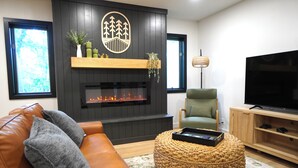A living room with a fireplace, a television, a sofa, and a chair.