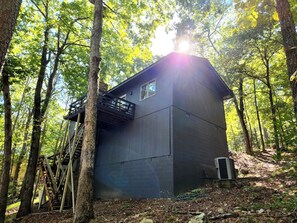 A cabin with a balcony, surrounded by trees.