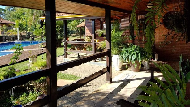Ein überdachter Außenbereich mit Pool, Holzterrasse und Topfpflanzen.