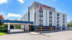A Hampton Inn hotel with a modern design, featuring a covered entrance and a clear sky.