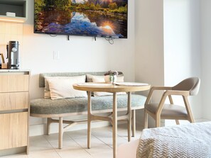 Een moderne woonkamer met een bank, een ronde tafel en een aan de muur bevestigde televisie.