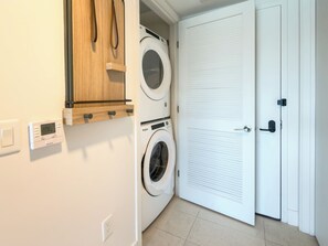 Een wasserette met een wasmachine, een droger en een houten kast.