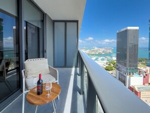 A balcony with a chair, a table, a bottle of wine, and a glass. - 3512 - Elegant Studio in Downtown Miami with a Pool and a 24/7 Gym (Miami)