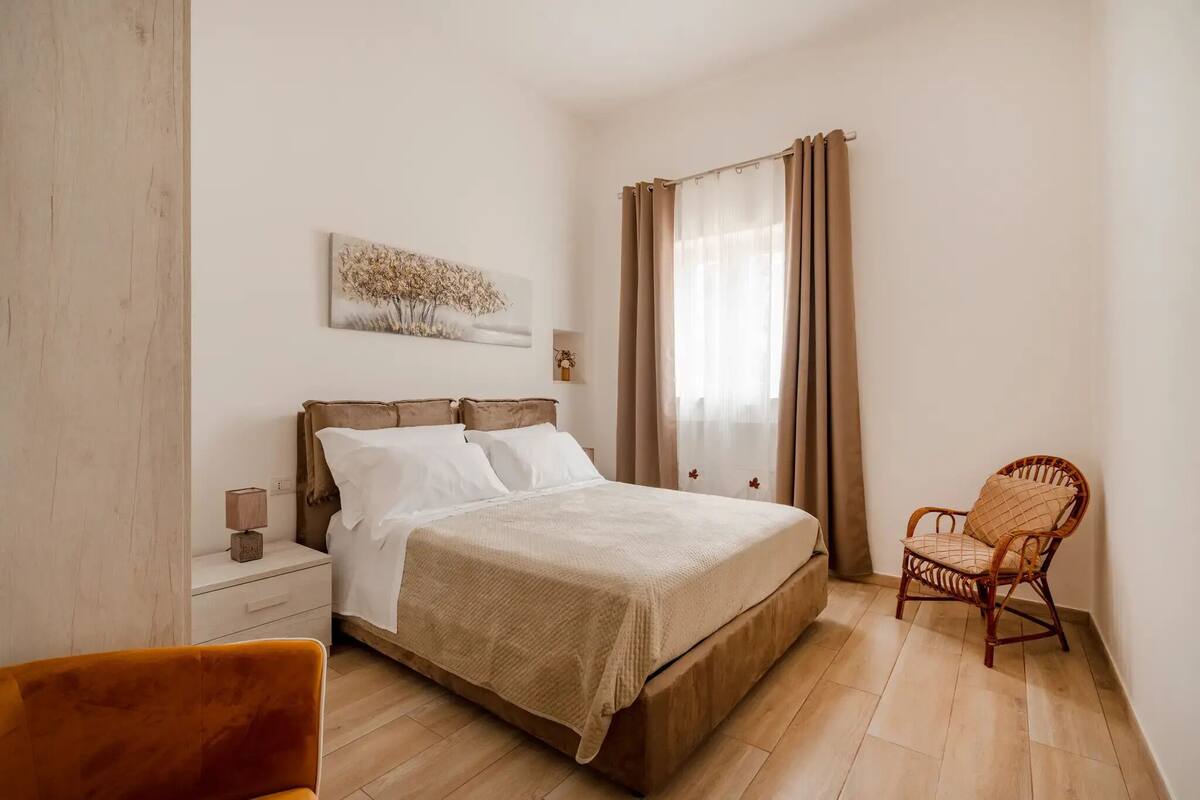 Une chambre à coucher avec un lit, une table de chevet, une chaise et un tableau accroché au mur.