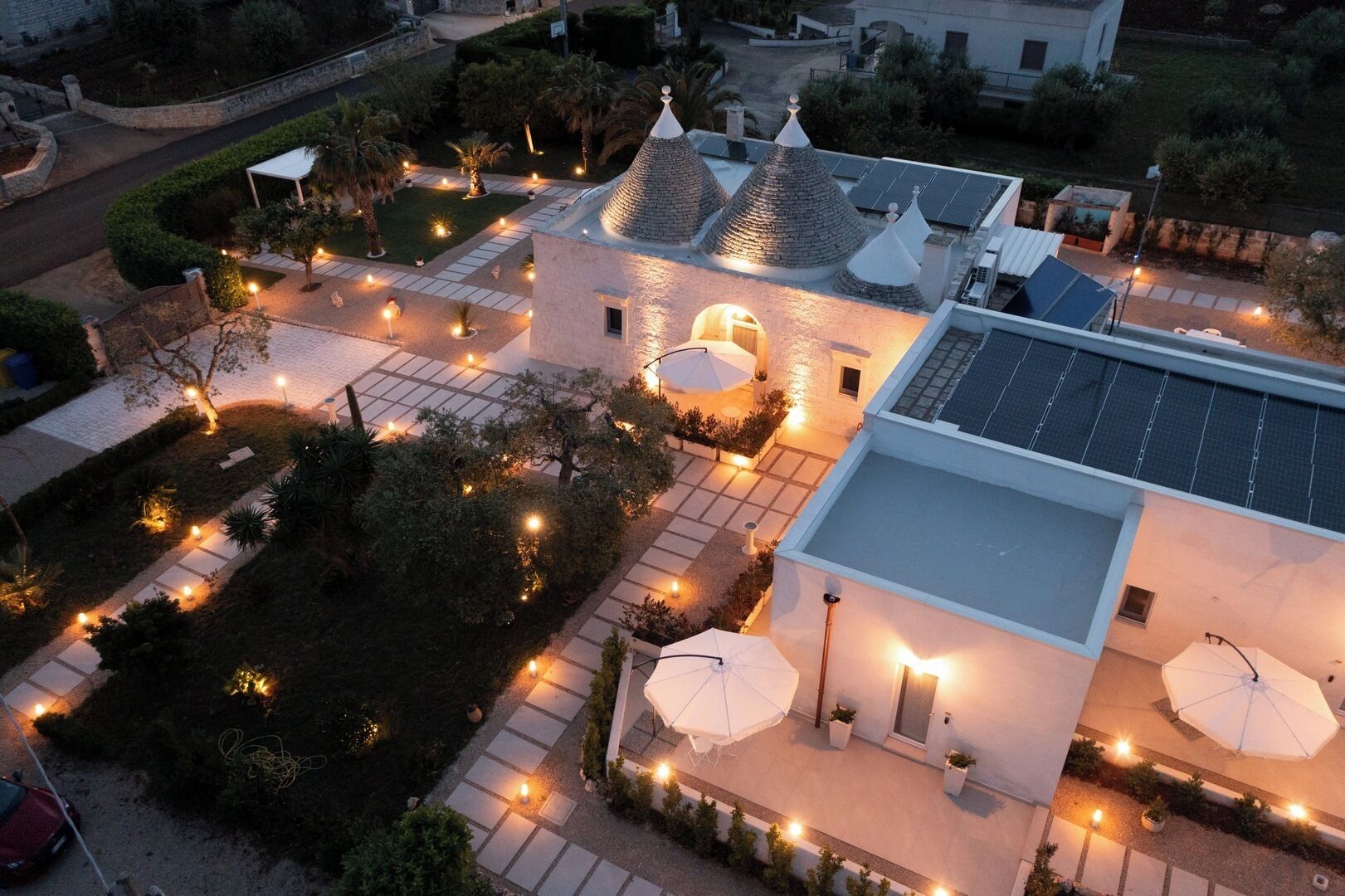 Un edificio moderno con jardín en la azotea, paneles solares y zonas de estar exteriores con sombrillas.