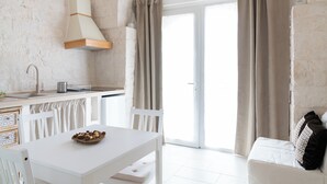 Una cocina moderna con armarios blancos, estufa integrada y comedor con mesa y sillas blancas.
