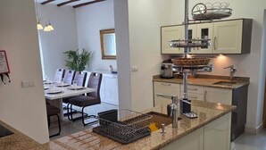 Une cuisine moderne dotée d’un plan de travail en granit, d’appareils électroménagers en acier inoxydable et d’un coin repas avec une table et des chaises.