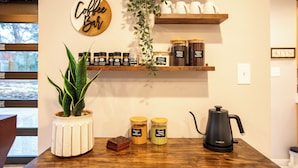 Une décoration sur le thème du café, avec un panneau représentant une tasse de café, des étagères remplies de pots de café, une machine à café et une plante en pot.
