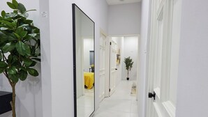 A hallway with a mirror, a potted plant, and a door leading to another room. - Luxurious 2BR/2BTH APT in New Kingston (Kingston)
