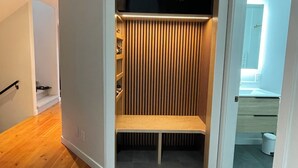 Ein moderner begehbarer Kleiderschrank mit vertikalen Holzleisten, einer Sitzbank und eingebauten Regalen.