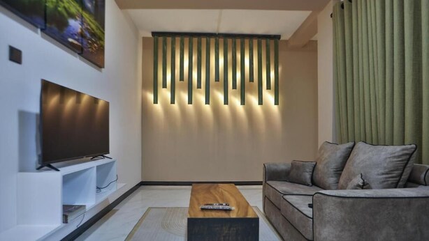 Una sala de estar moderna con una televisión de pantalla plana, una mesa de centro de madera y un sofá gris.