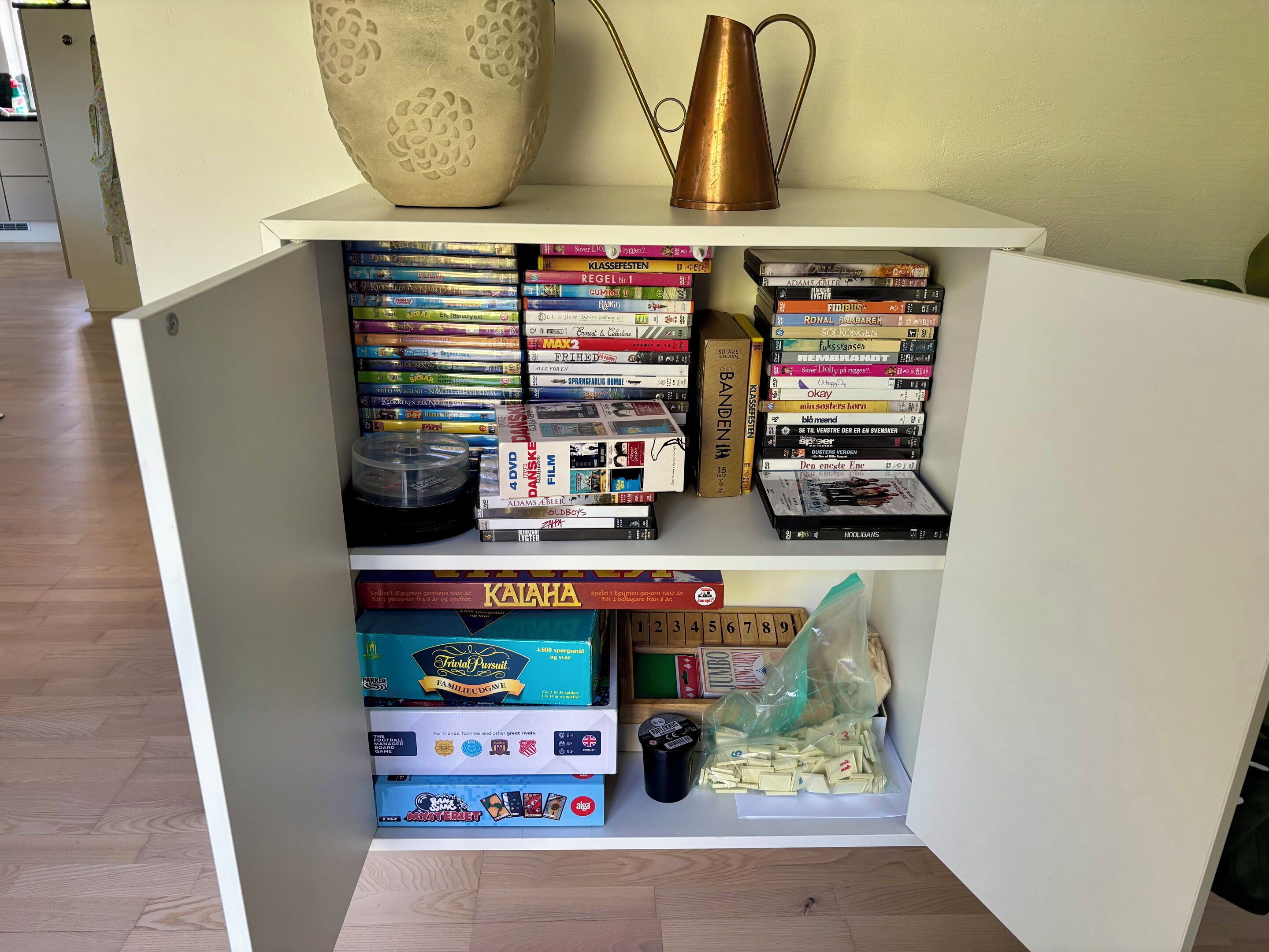 A shelf with books, DVDs, and board games.