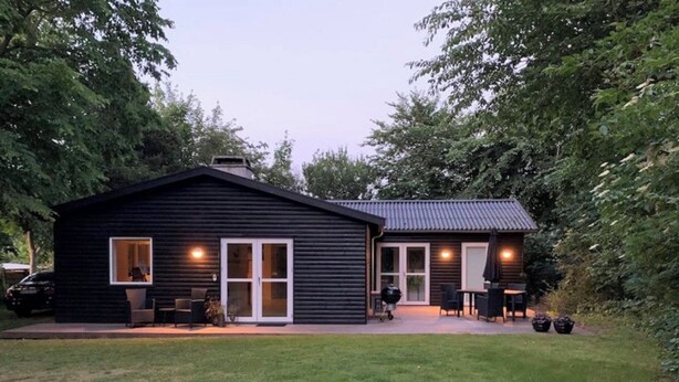A two-story cabin with a patio area, large windows, and a grill. - Bright holiday home in green surroundings (Vejby)