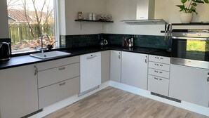 A modern kitchen with a window, built-in appliances, and a potted plant. - Bright holiday home in green surroundings (Vejby)