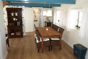 A dining area with a wooden table, wicker chairs, a sideboard with baskets, and a blue ceiling. - Charming thatched-roff house with two floors (Rudkøbing)