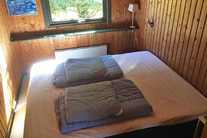 A wooden-paneled room with a bed, a window, and a wall-mounted lamp. - holiday home located on a 1400 m plot (Rudkøbing)
