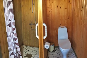 Ein Badezimmer mit Holzpaneelen, einer Duschvorhang, Toilette und einer Toilettenpapierrolle.