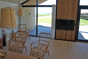 A room with wicker chairs, a large window, and a flat-screen TV. - Nice holiday home 100 meters from the water (Rudkøbing)