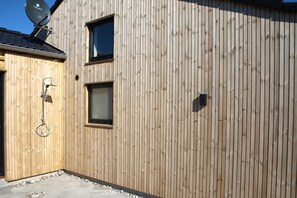 A wooden exterior wall with a satellite dish, a window, and a door. - Nice holiday home 100 meters from the water. (Rudkøbing)
