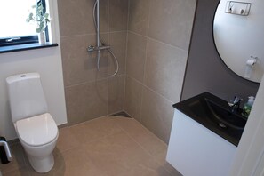 A bathroom with a toilet, shower, sink, and a window with a plant. - Nice holiday home 100 meters from the water (Rudkøbing)