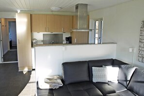 A modern kitchen with wooden cabinets, a stainless steel range hood, and a built-in coffee maker. - Holiday home just 400 meters from the water (Rudkøbing)